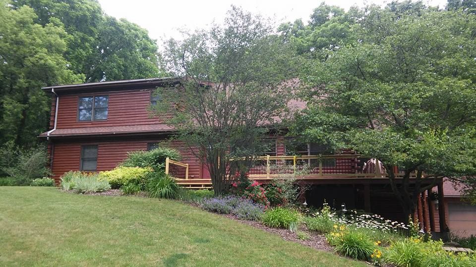 A large house with a large deck is surrounded by trees