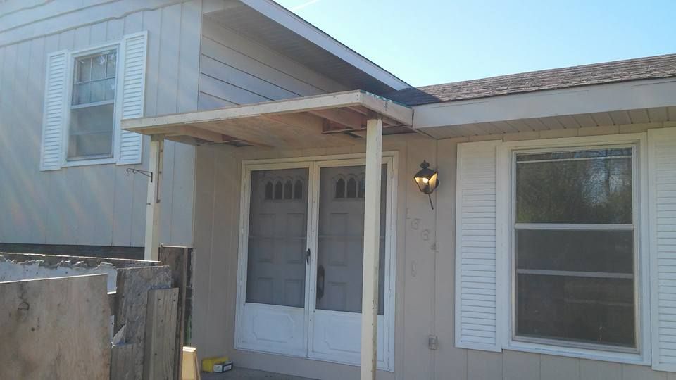 A white house with a porch and shutters on the windows.