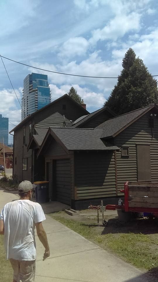 A man is walking down a sidewalk in front of a house.