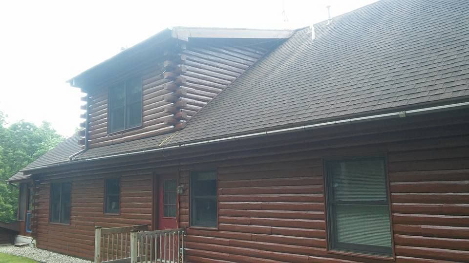 A log cabin with a brown roof and a red door.