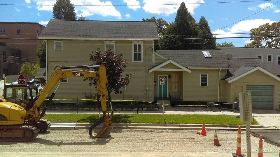 A yellow excavator is parked in front of a house