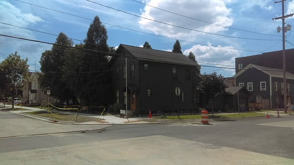 A black house sits on the corner of a street