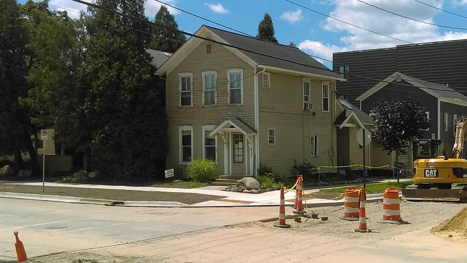 A cat excavator is parked in front of a house