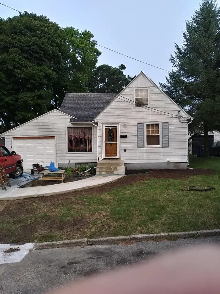 A white house with a red truck parked in front of it