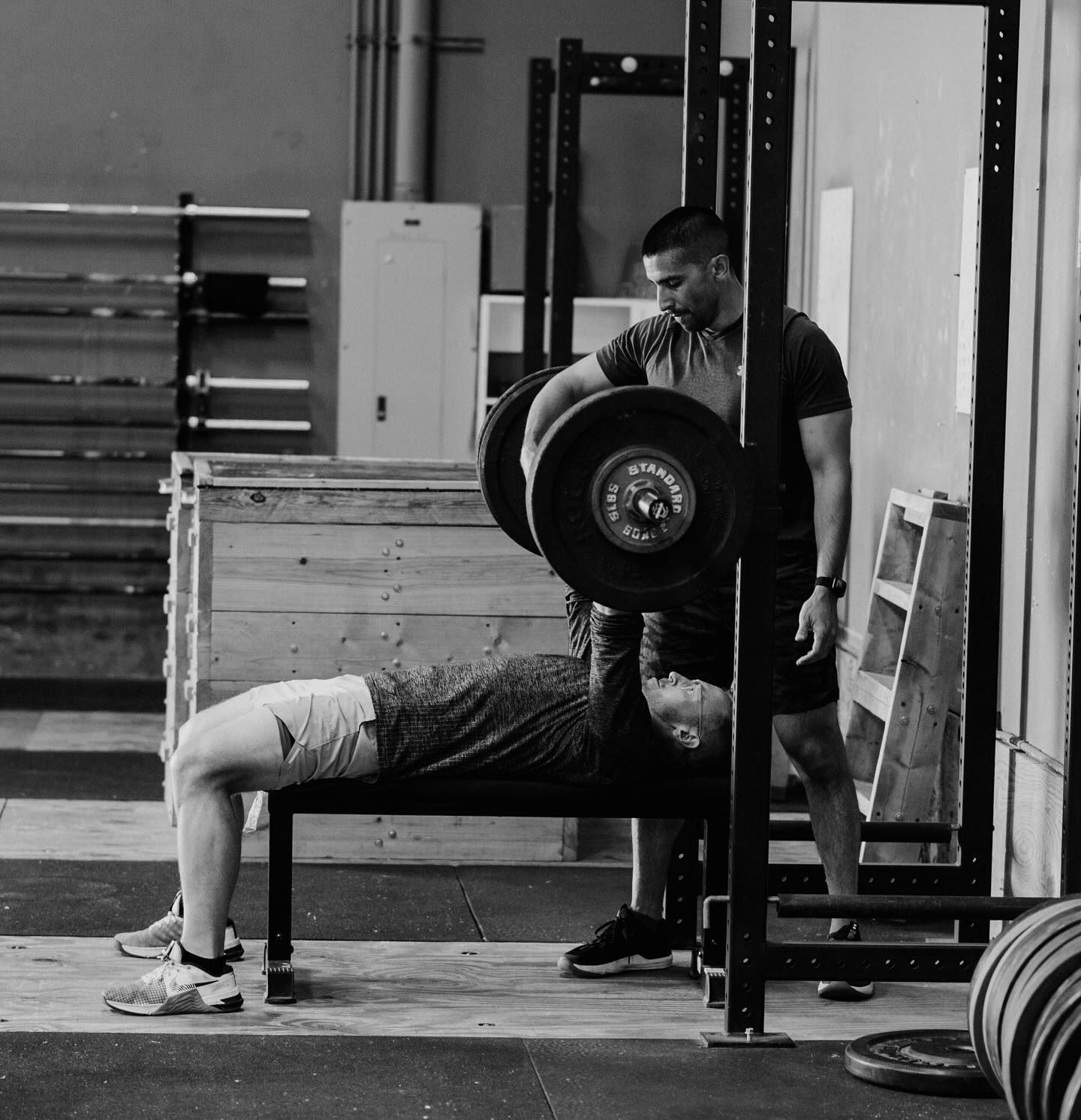 A black and white photo of a man lifting a barbell