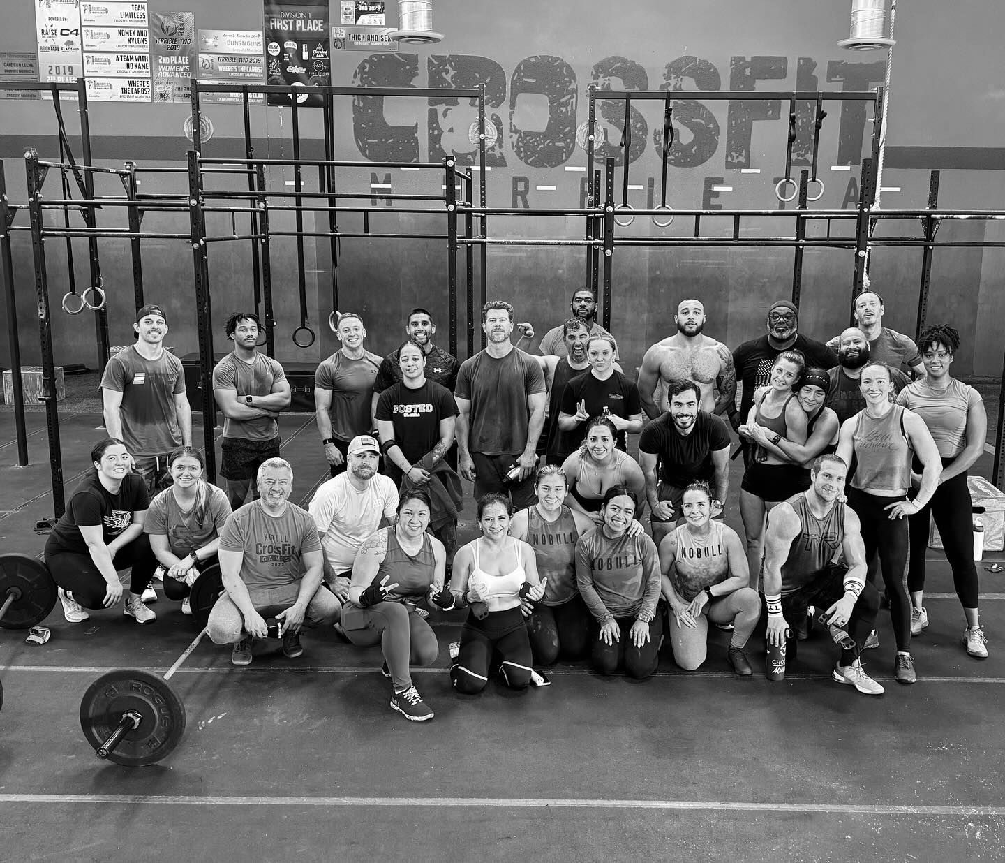 A group of people are posing for a picture in a gym.