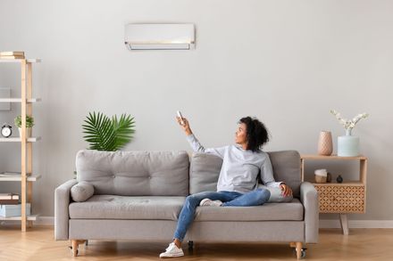 a woman is sitting on a couch holding a remote control .