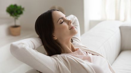 a woman is sitting on a couch with her eyes closed .