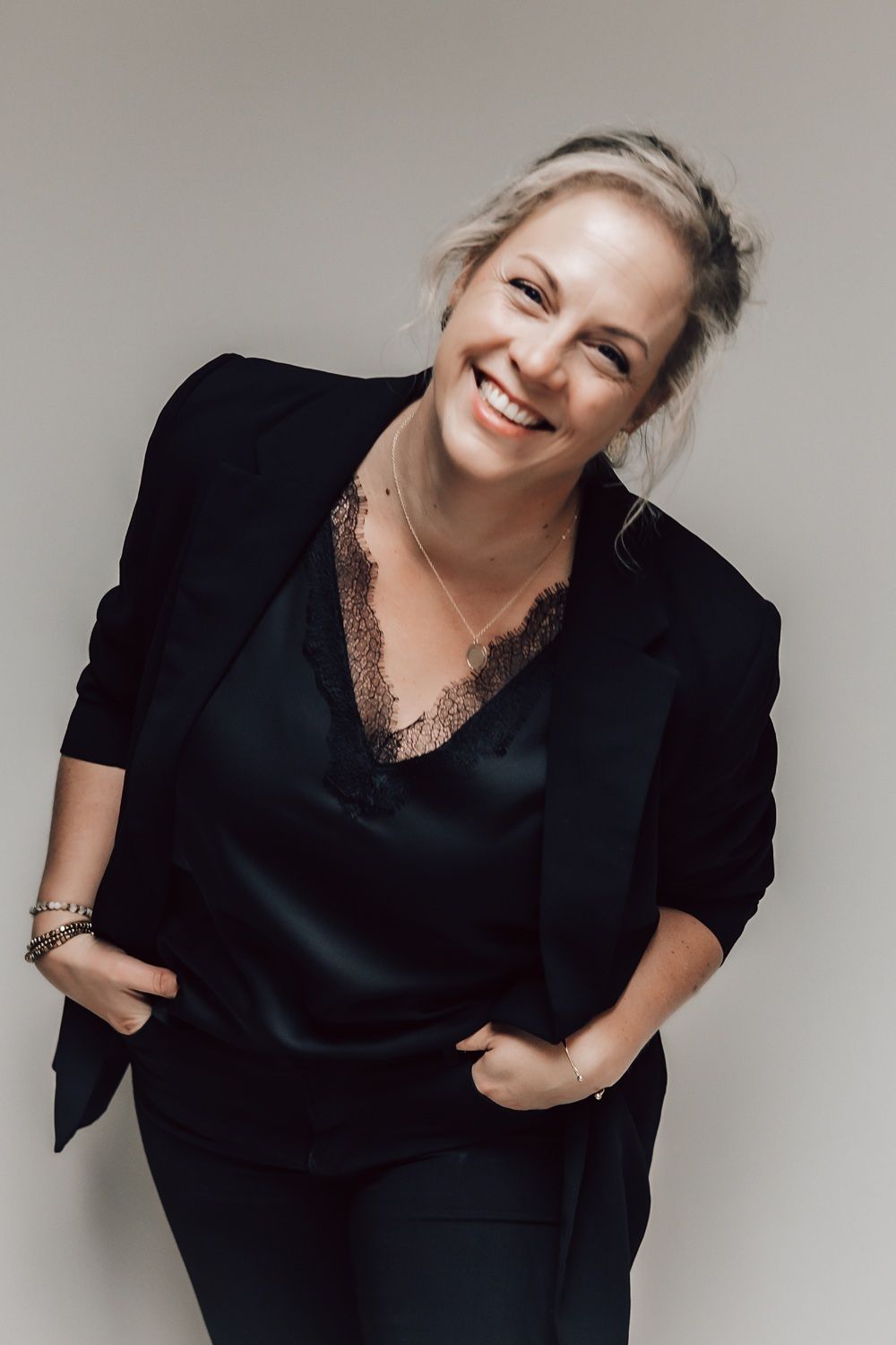 Annet draagt ββeen zwart jasje en een zwart topje en lacht.