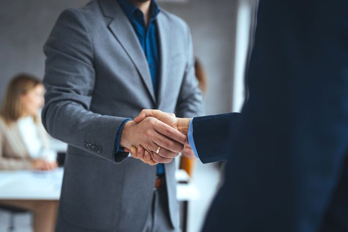 A man in a suit is shaking hands with another man in a suit.