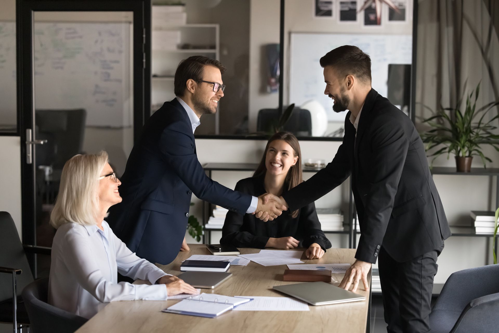 A group of business people are shaking hands while sitting at a table.