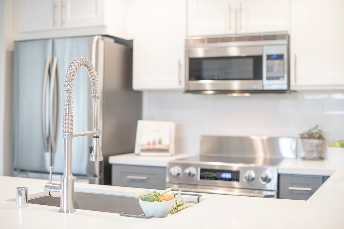 Modern kitchen with stainless steel sink and pull-down faucet, white cabinets, and stainless appliances.