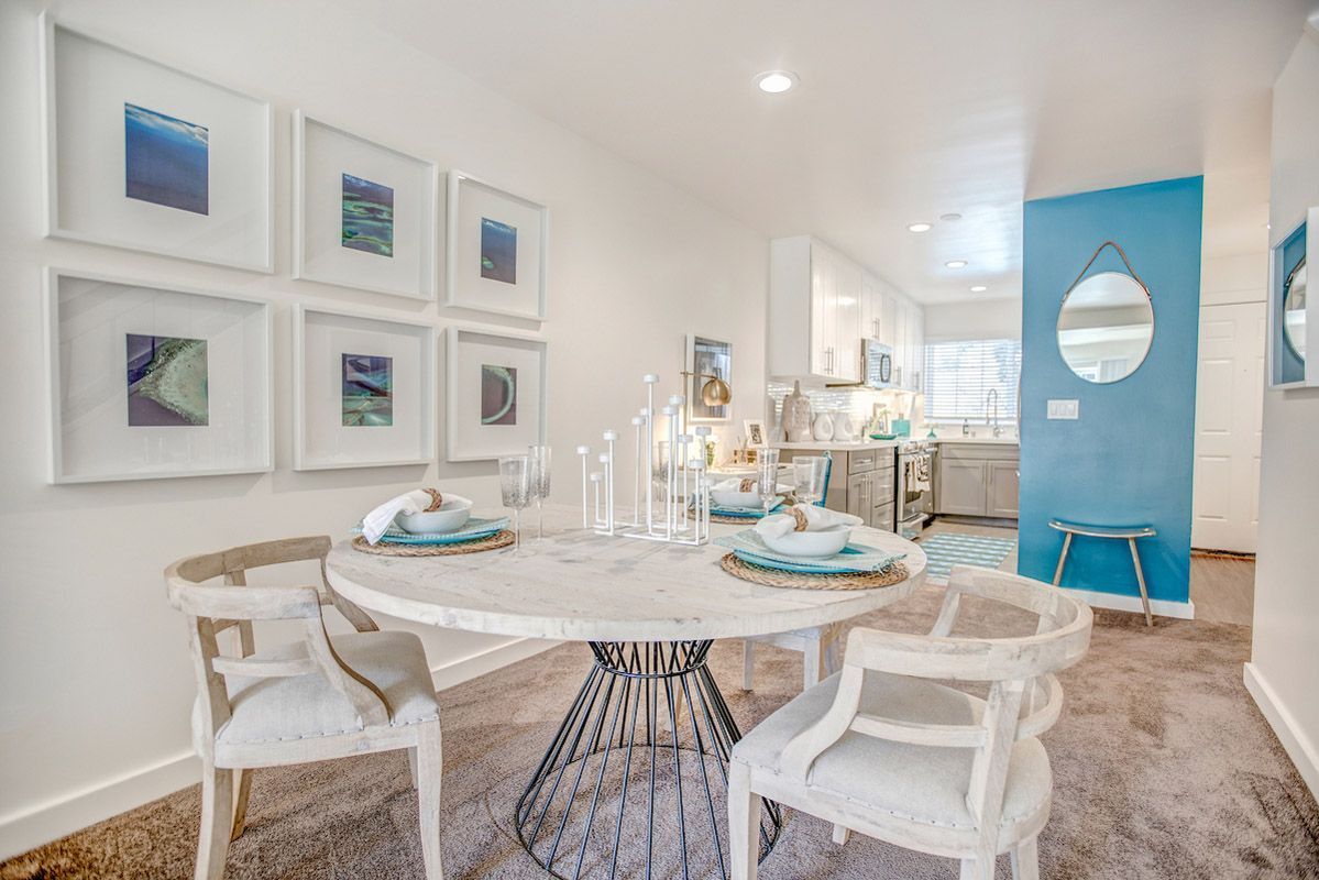 Round marble dining table with four white chairs in a bright open-concept kitchen.