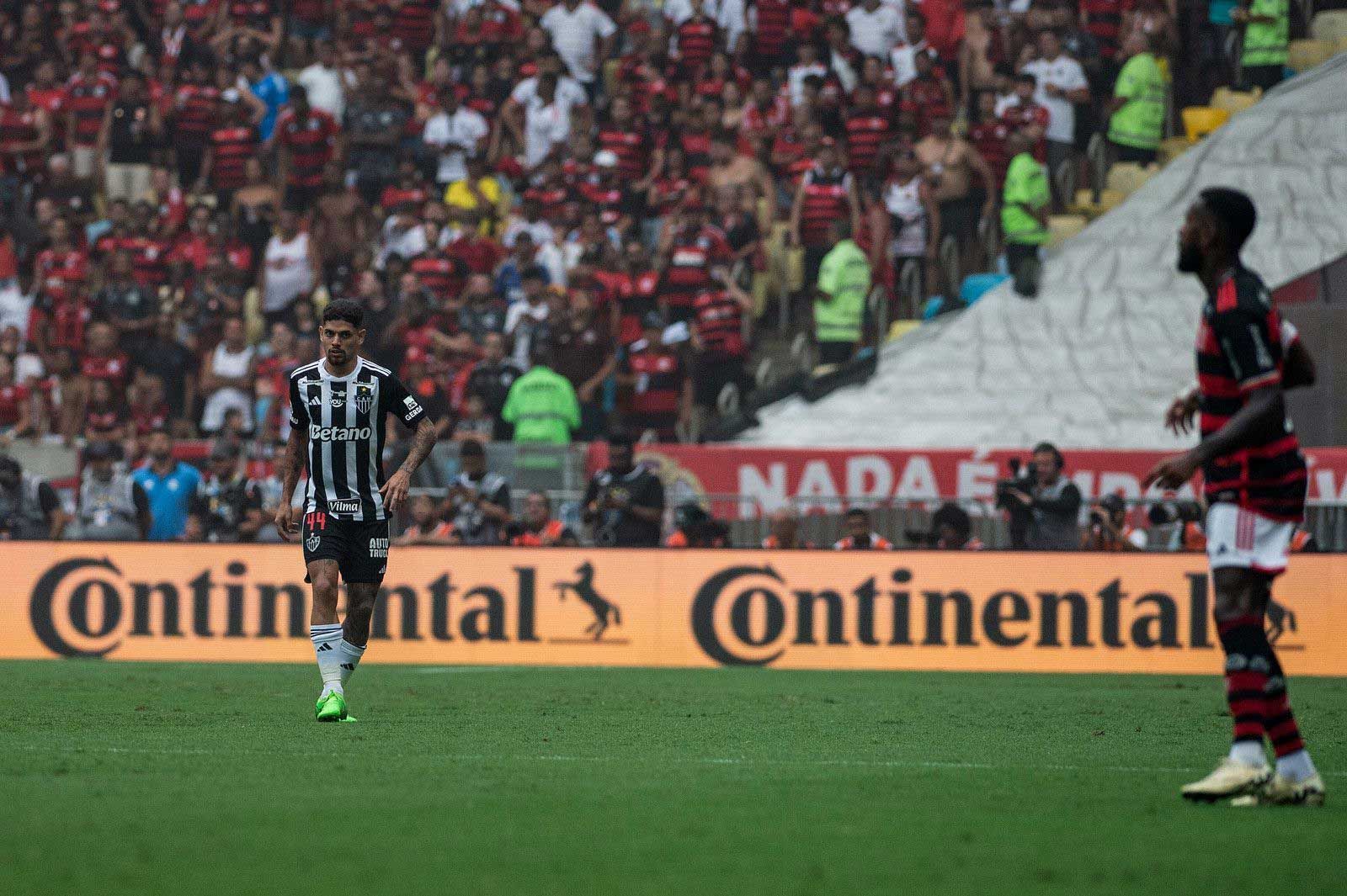 Dois jogadores de futebol estão em um campo em frente a um anúncio do continental.
