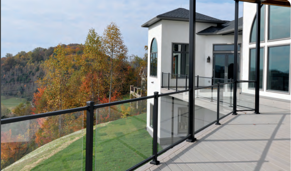A balcony with a glass railing and a view of a house.
