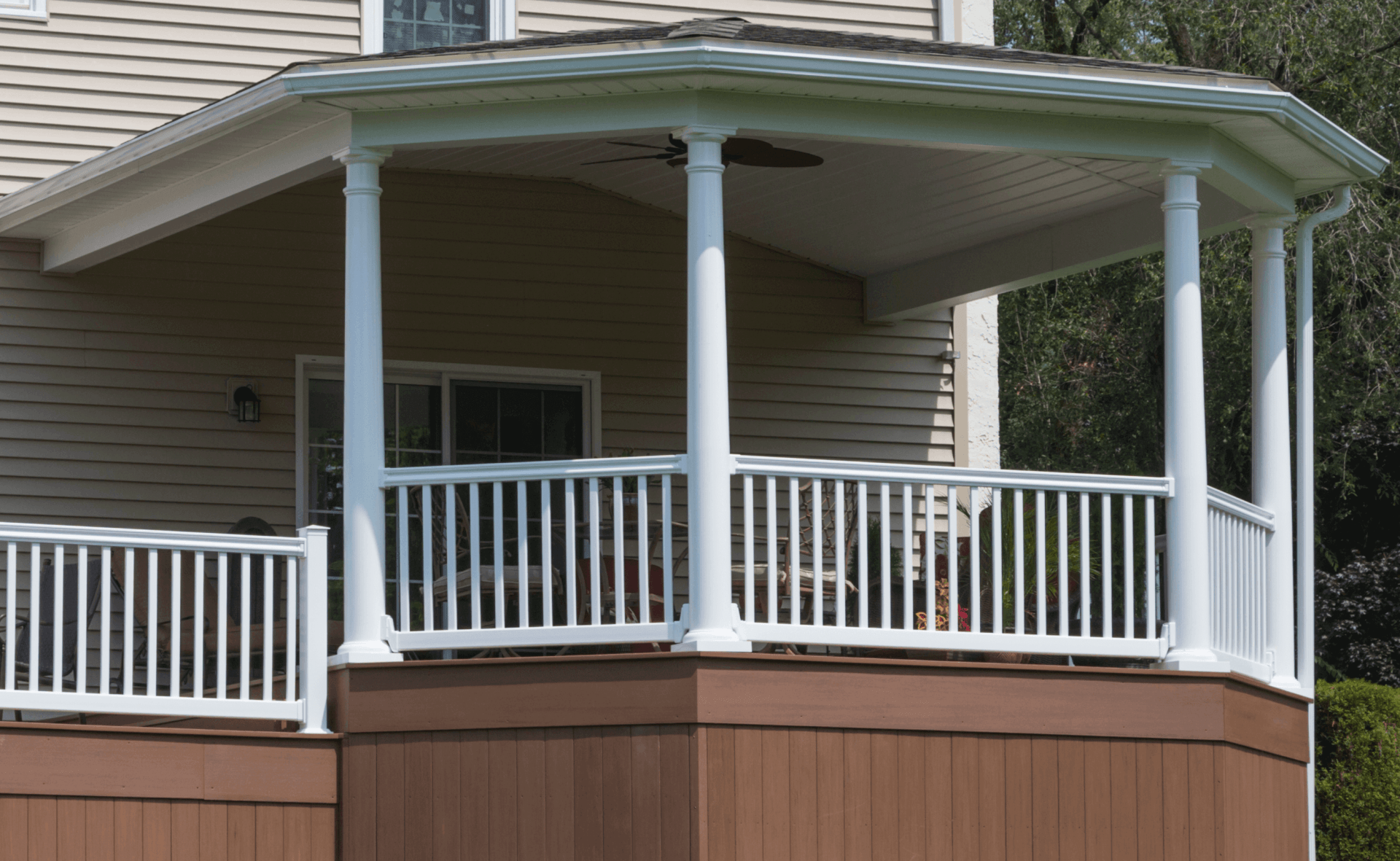 A porch with a white railing and a ceiling fan