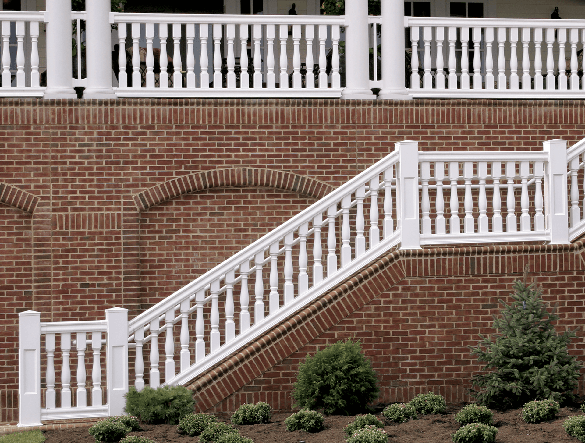 A brick wall with stairs and a white railing