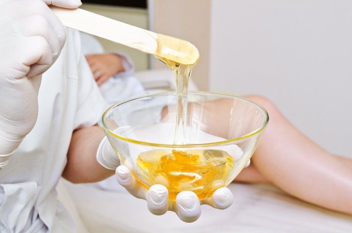 Cosmetologist master holding bowl with hot wax