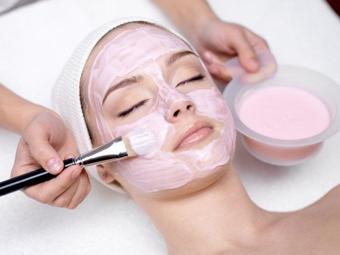 Girl receiving cosmetic pink facial mask