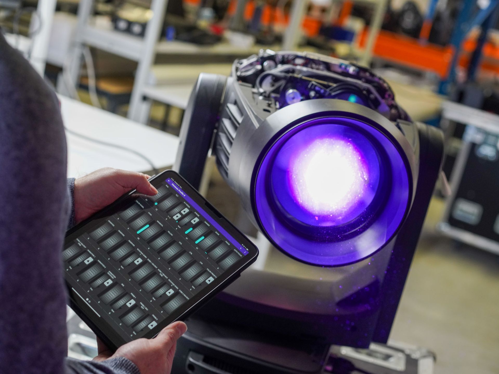 Eine Person hält ein Tablet vor ein violettes Licht.