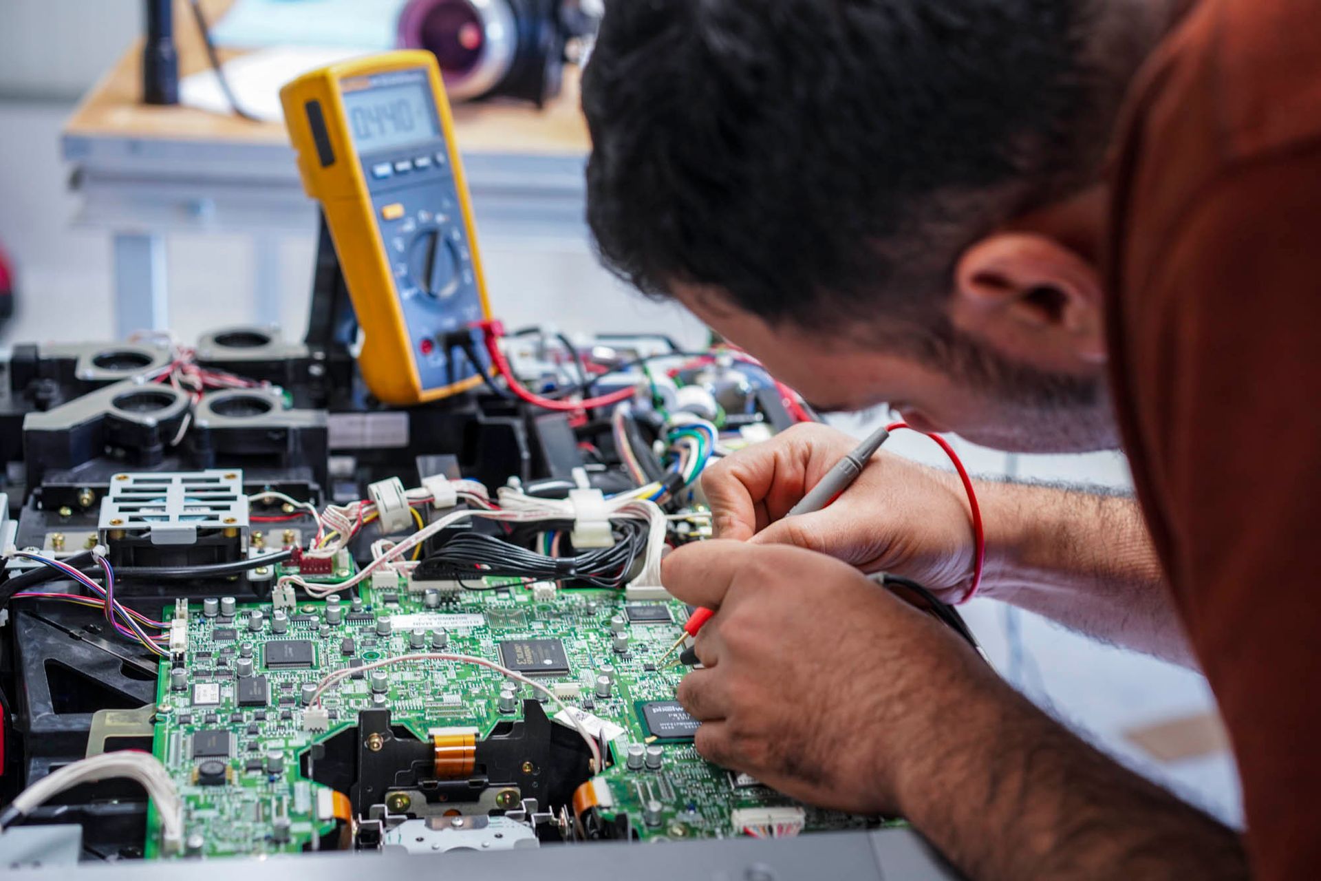 Ein Mann arbeitet mit einem Multimeter an einer Hauptplatine.