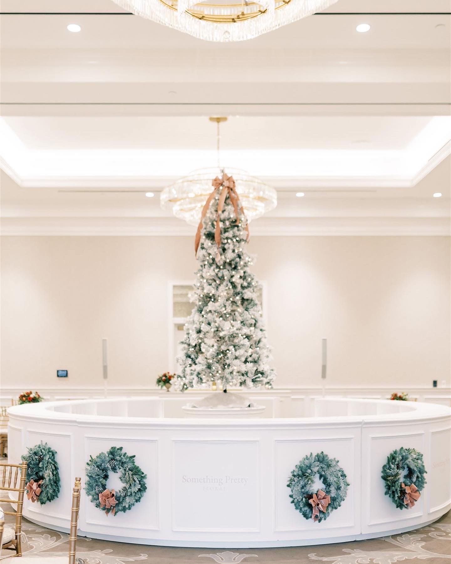 A decorated Christmas tree and bar, with wreaths, in a festive hall.