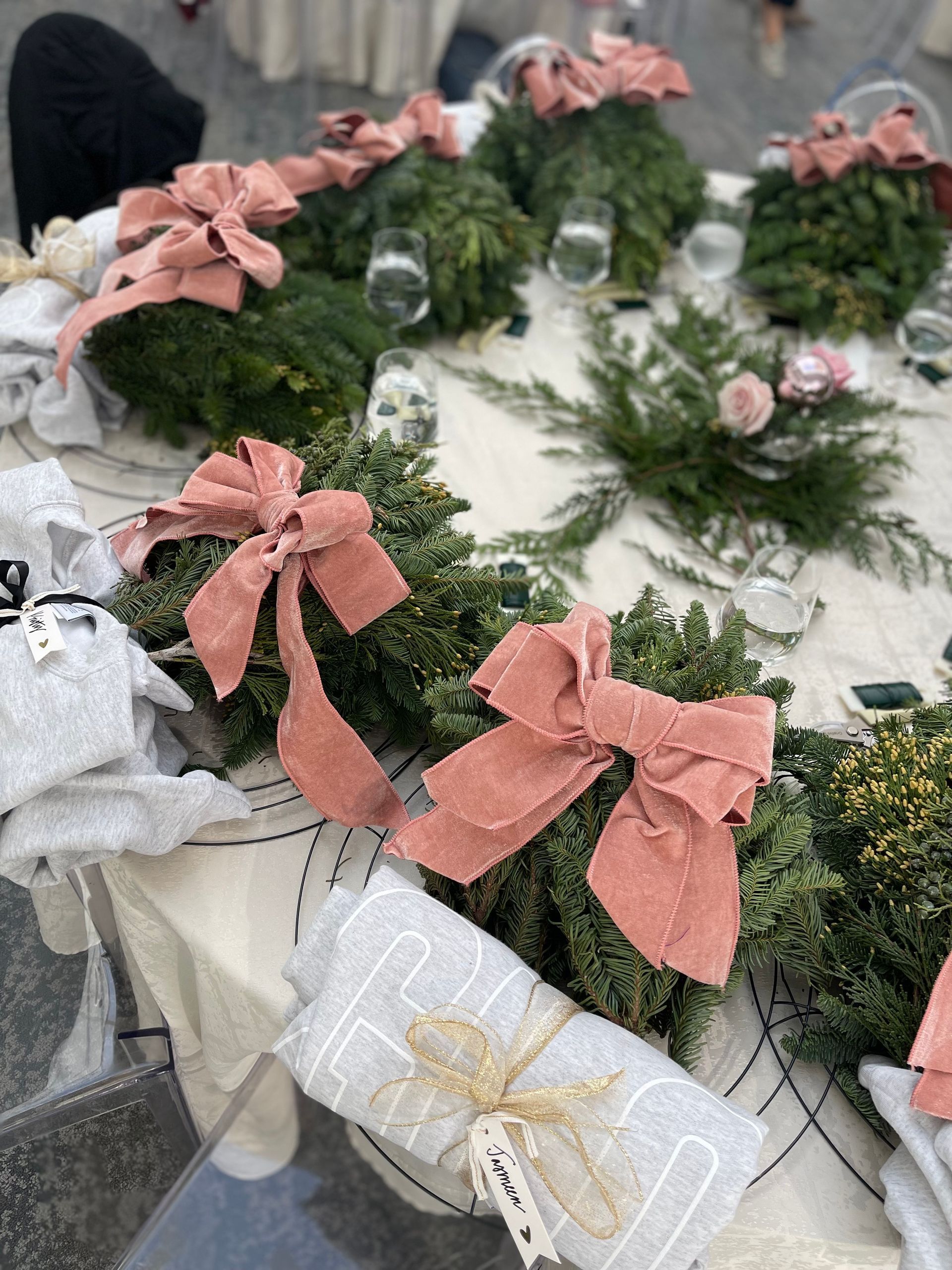 Table setting with green wreaths, pink bows, and gifts.