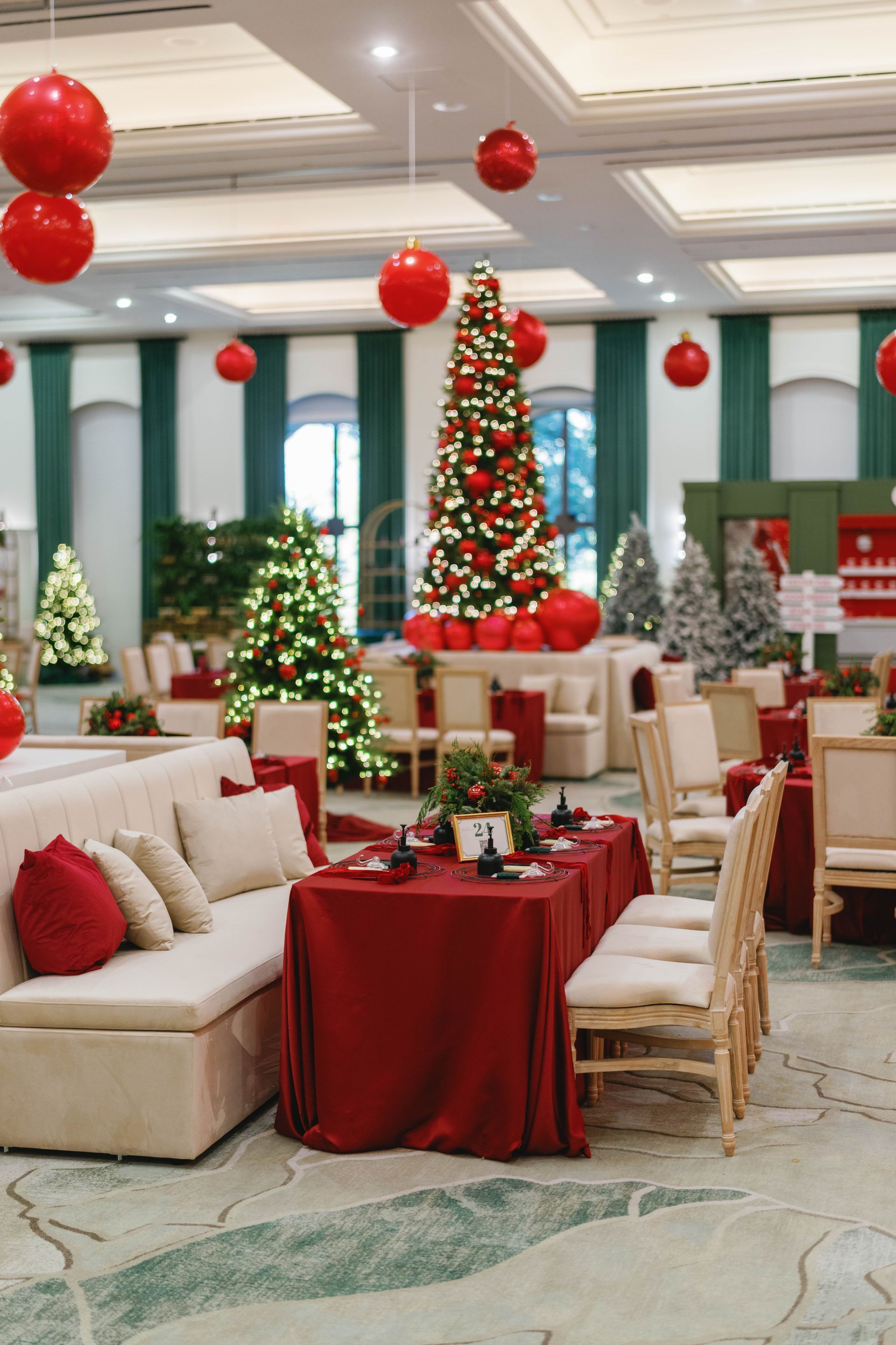 A festive dining room decorated for Christmas with red and green decor, trees, and tables.
