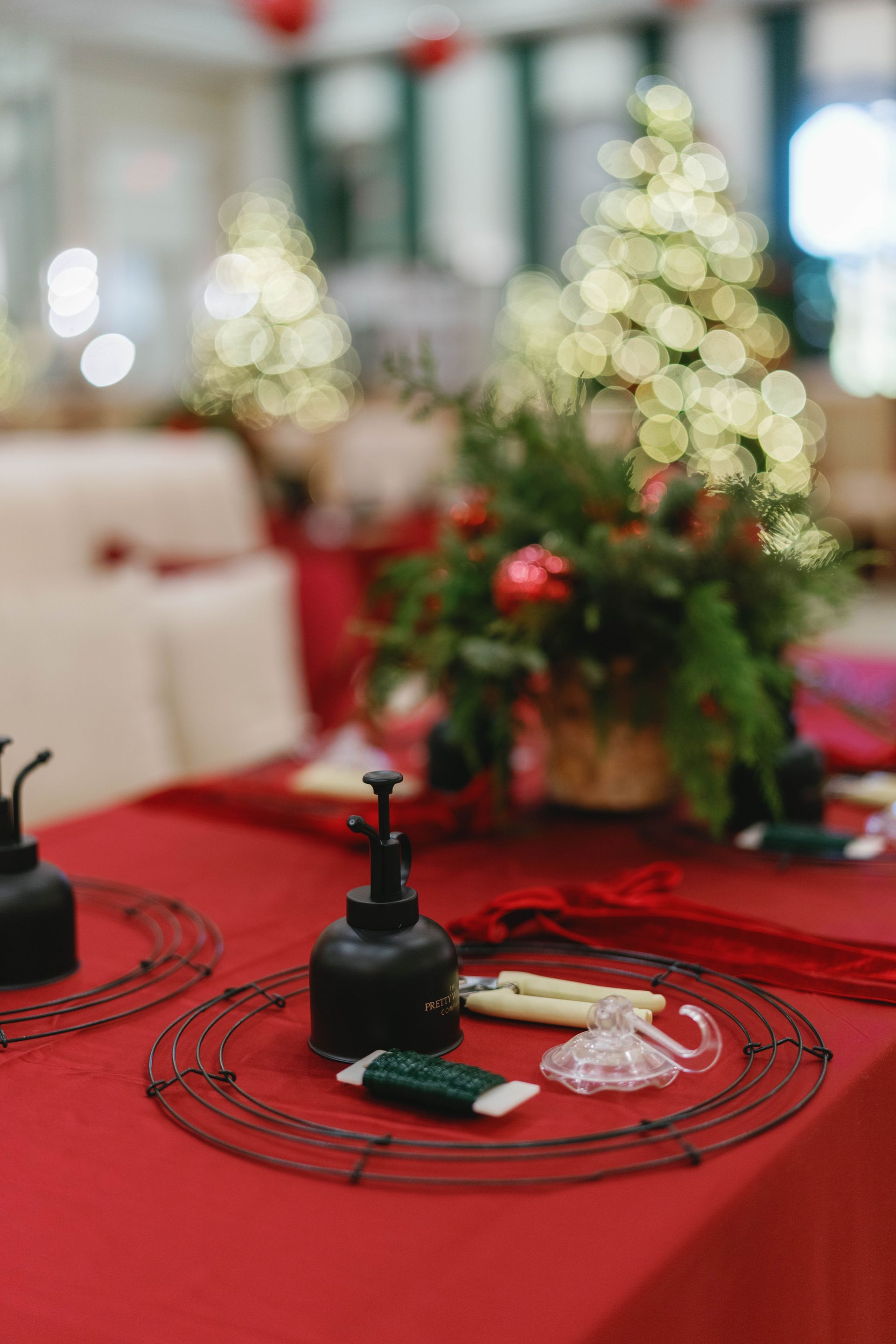 Red tablecloth with Christmas centerpiece, tools. Softly lit room.