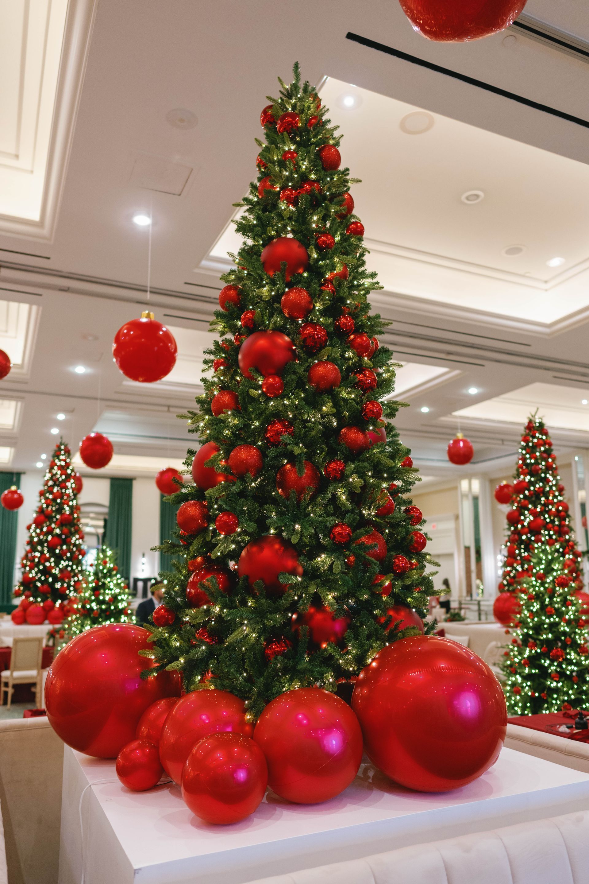 Christmas trees decorated with red ornaments in a festive setting.
