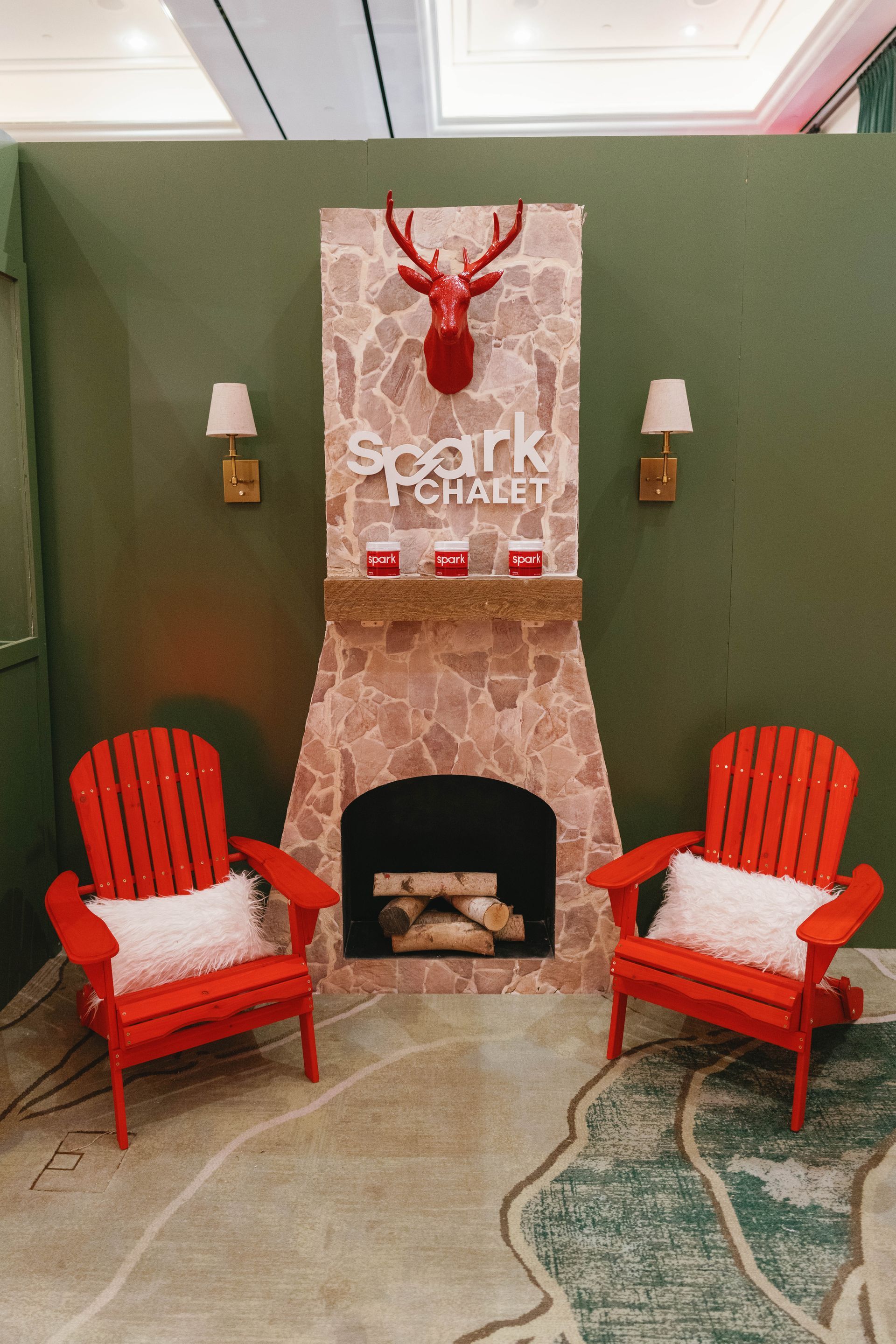 Red chairs face a fireplace display with a red deer head and 