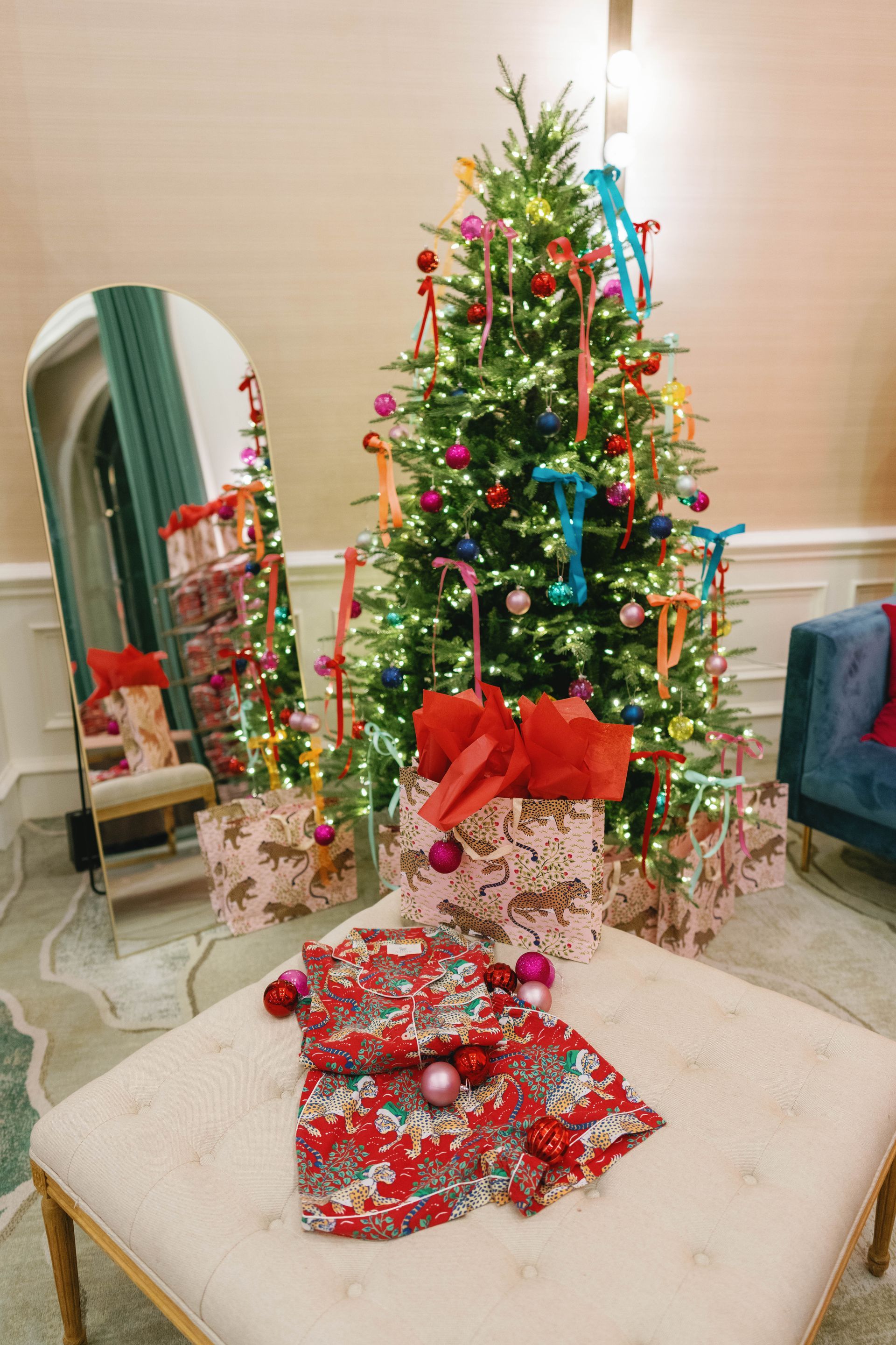 Christmas scene: tree with colorful ornaments and ribbons, wrapped gifts, and patterned pajamas.