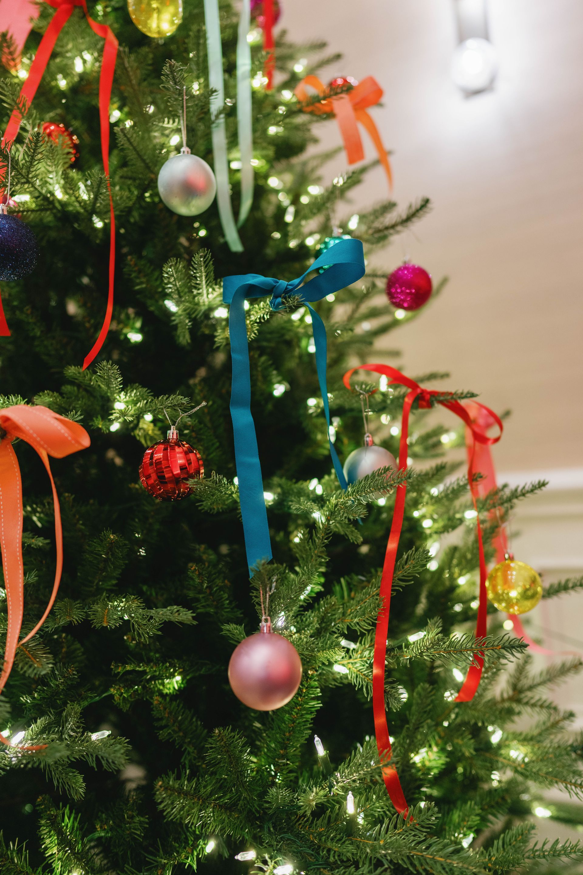 Christmas tree with colorful ornaments and ribbons; soft, warm lighting.