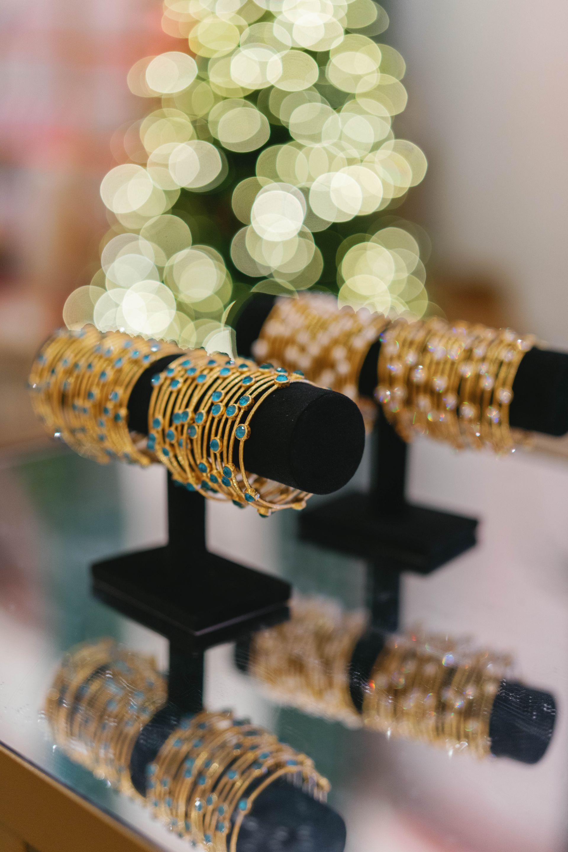 Gold bangles on display stand in front of Christmas tree lights.