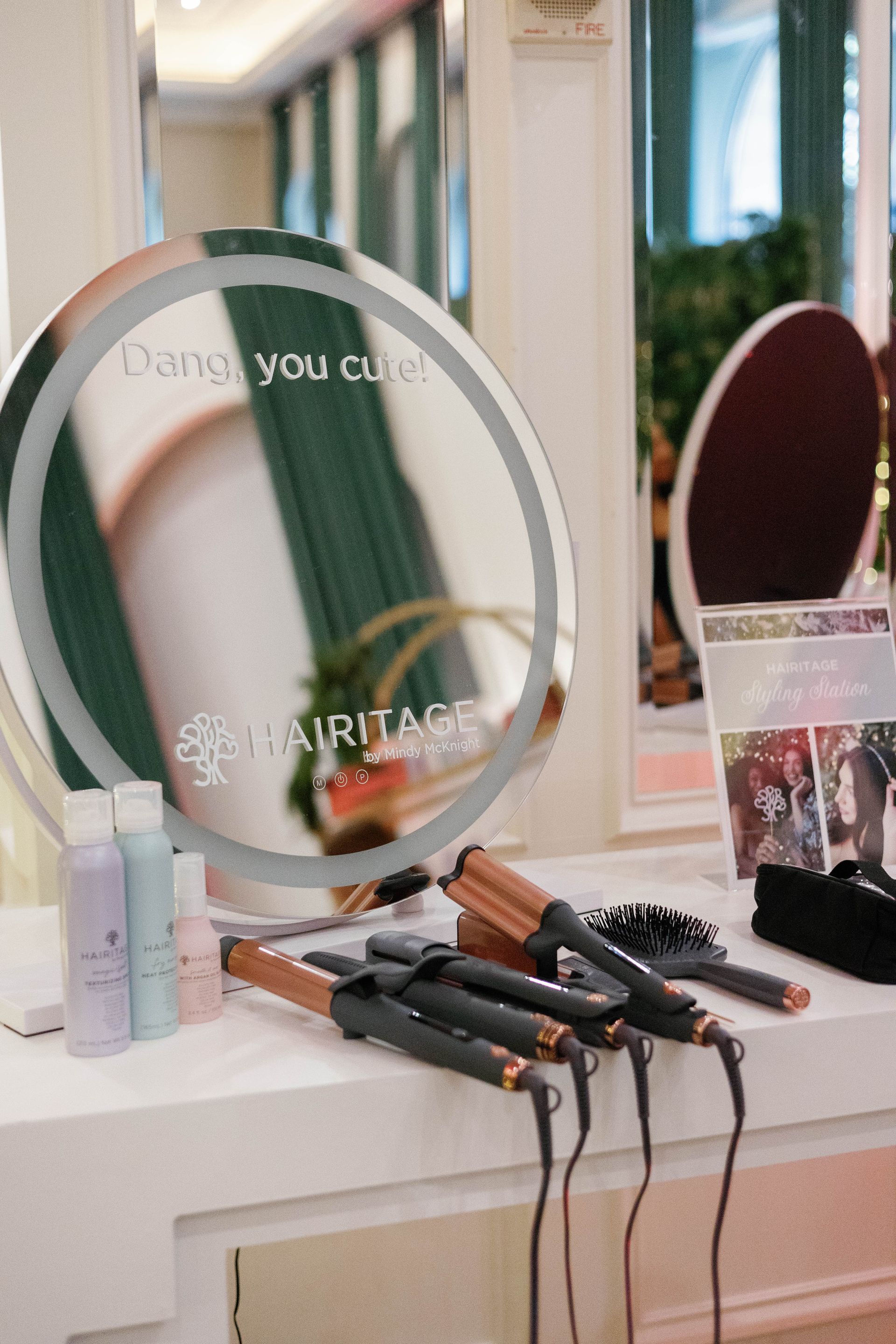 A beauty salon setup with curling irons, products, and a lit-up mirror.