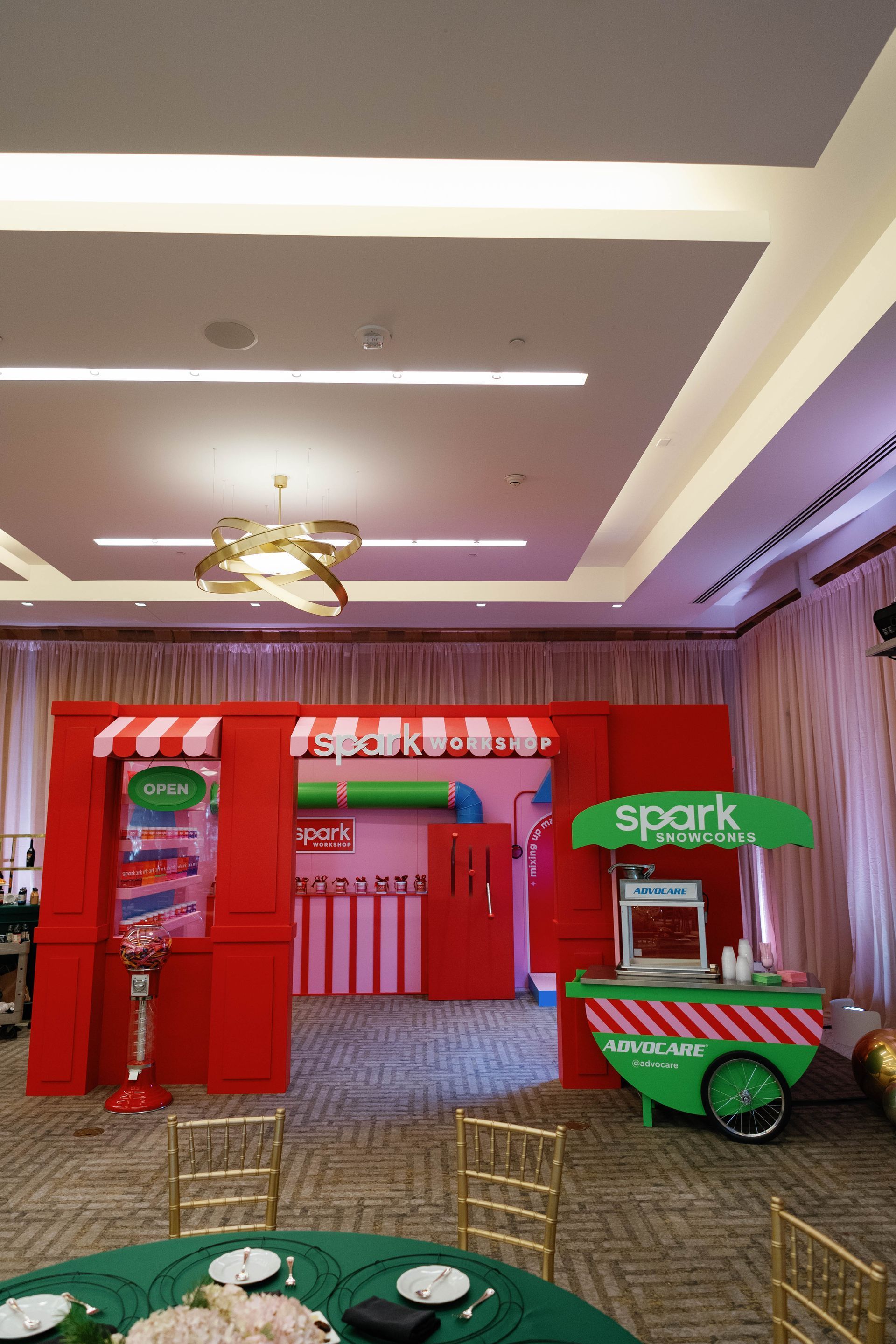 Event setup: red storefront backdrop and green food cart in a venue.
