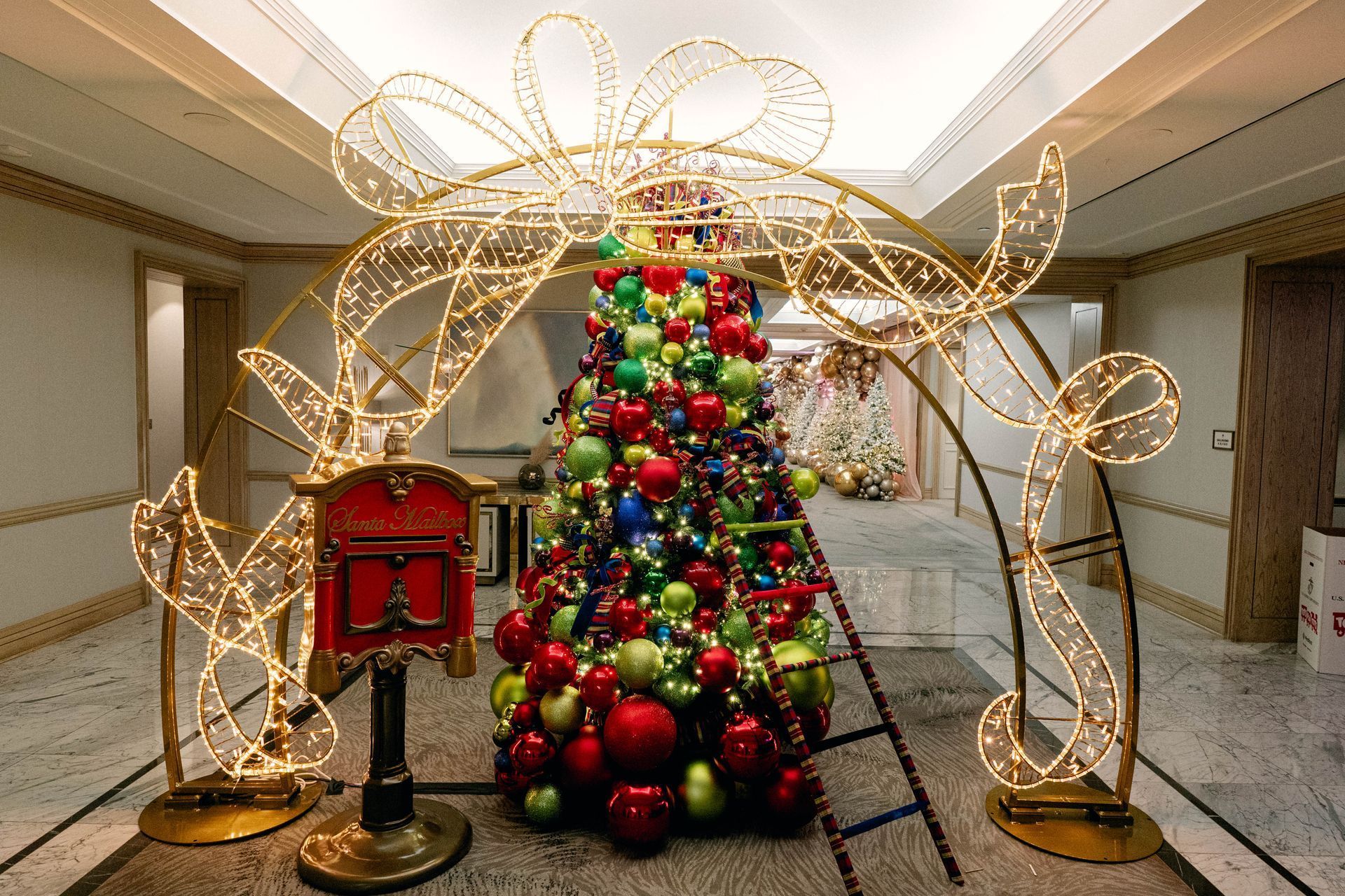 Christmas tree and decorations inside, with a large, lit bow arch and a red mailbox.