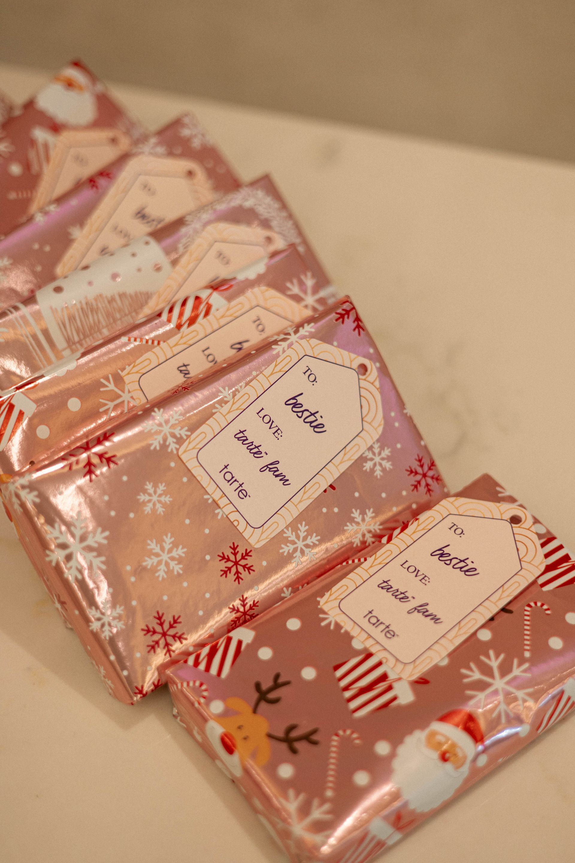 Pink wrapped holiday gifts with gift tags.