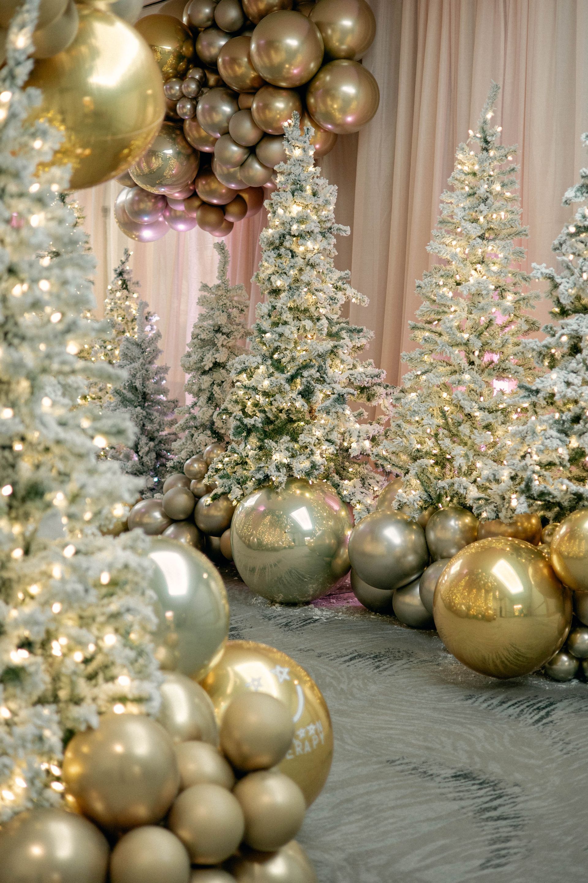 Flocked Christmas trees and gold balloons, festive holiday scene.