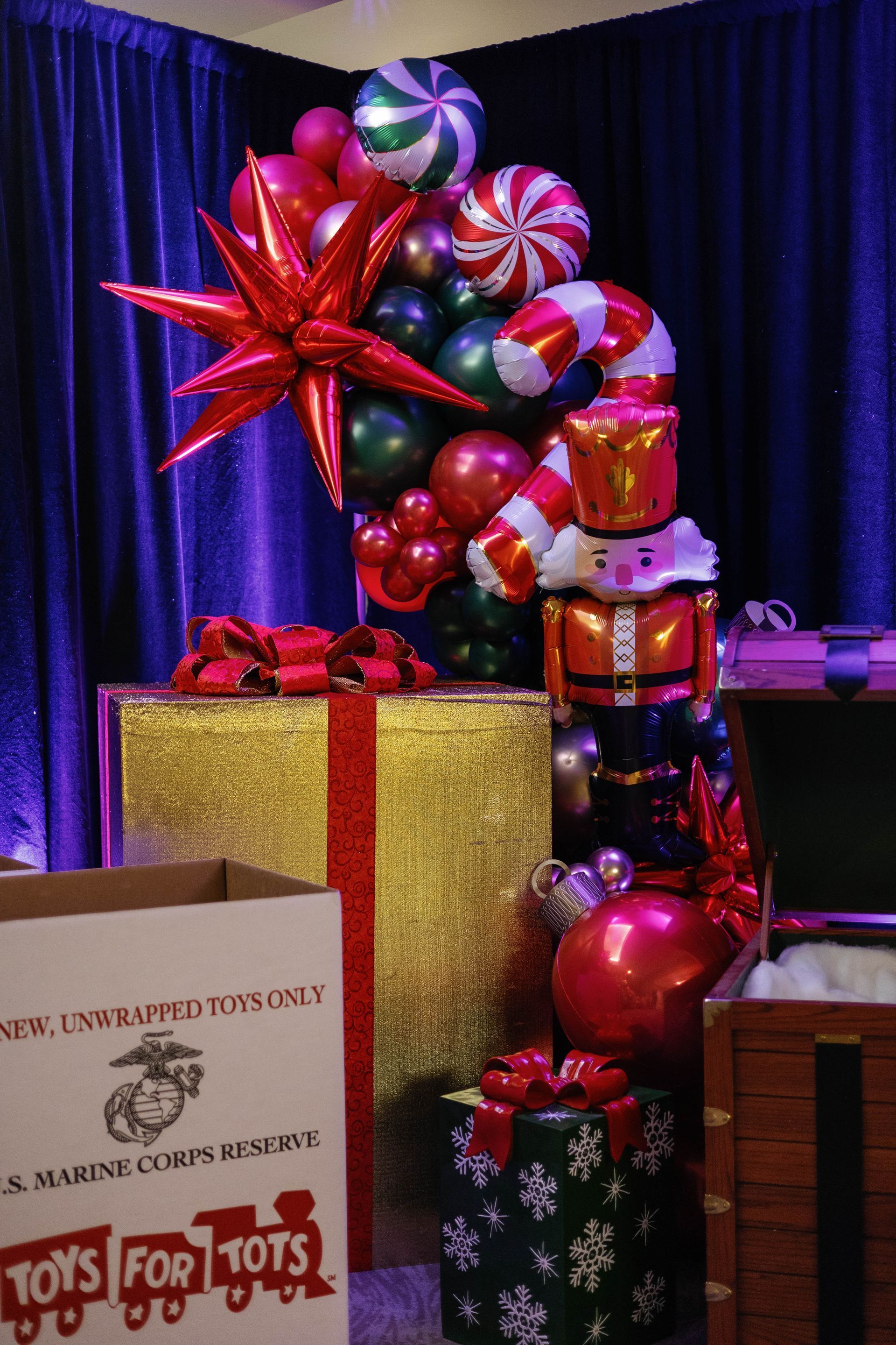 Christmas display with wrapped gifts, toy soldier balloons, and a Marine Toys for Tots box.