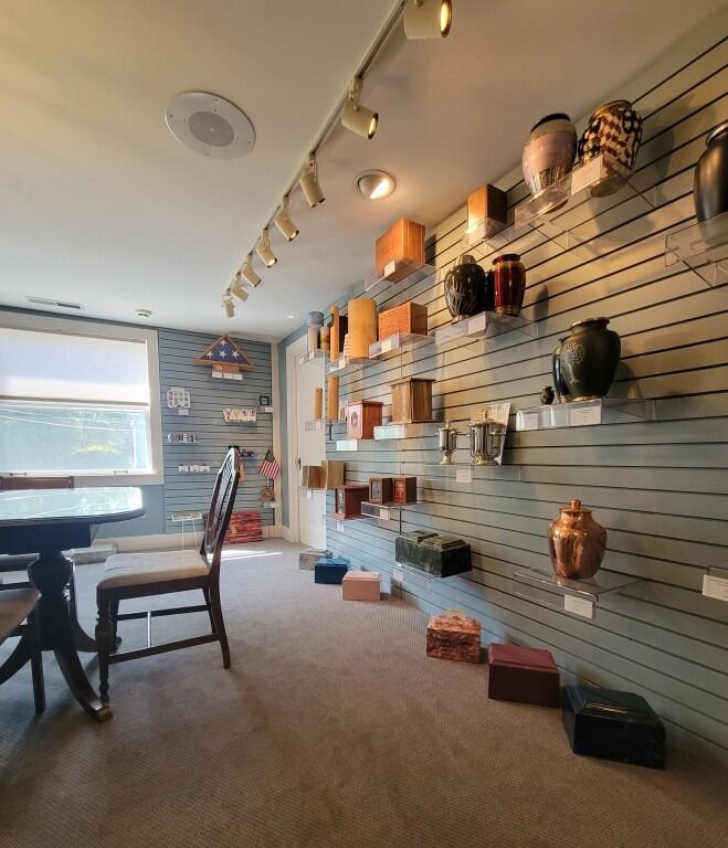 Room displaying various urns and boxes on shelves, with a chair and window visible.