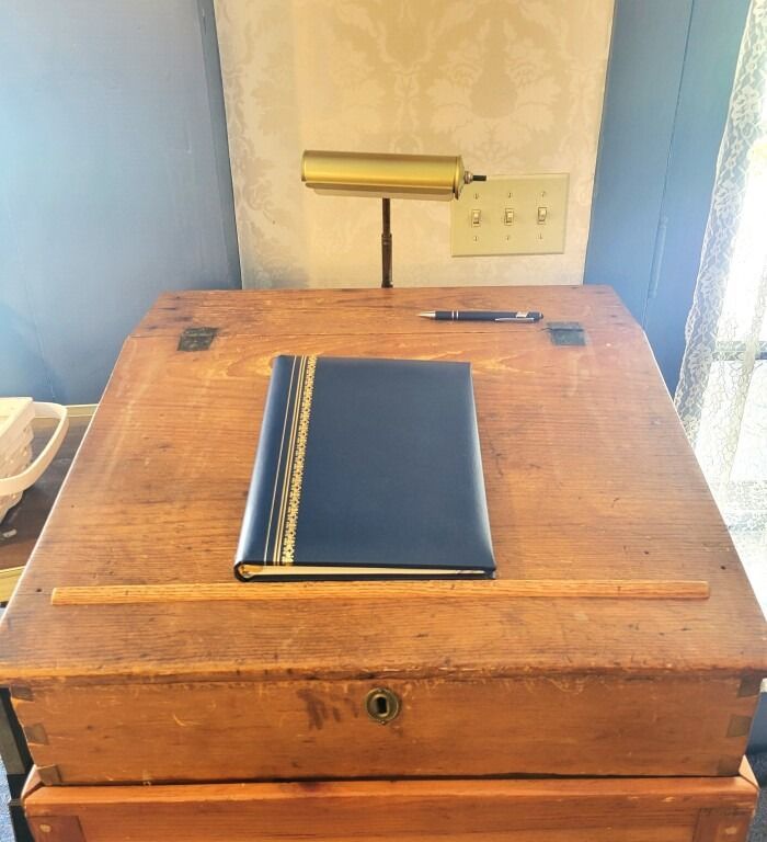 Wooden desk with a blue book, pen, lamp, and ruler on top.
