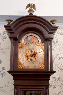Wooden grandfather clock with gold accents and eagle top.