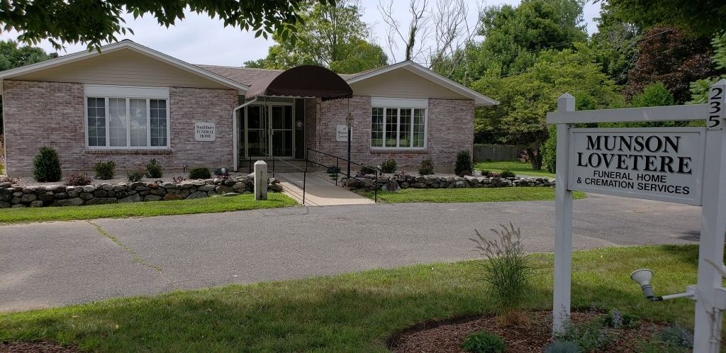 A light brick building with a brown awning and a sign for Munson Loveltere.
