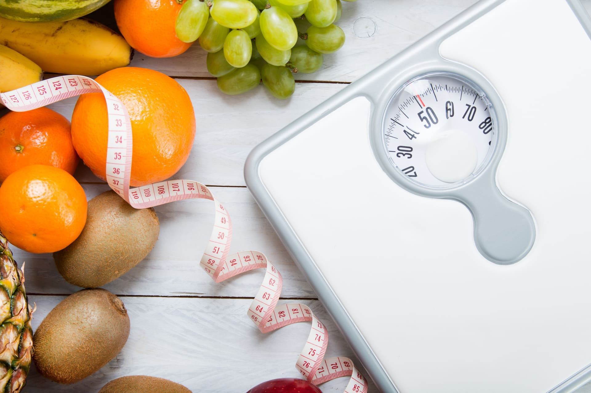 Stack of fruits, white weight scale and tailor meter on wooden board