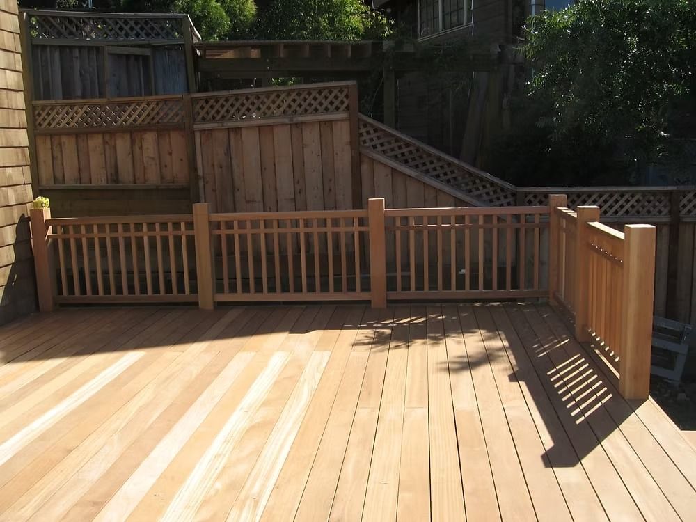 A chain link fence is surrounded by a wooden fence in a backyard.