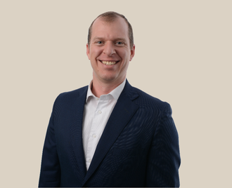 A man in a suit and white shirt is smiling for the camera.