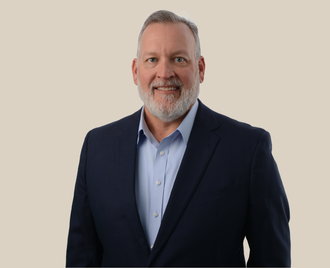 A man with a beard is wearing a suit and smiling.