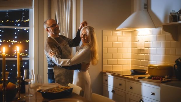 A man and a woman are dancing in a kitchen.