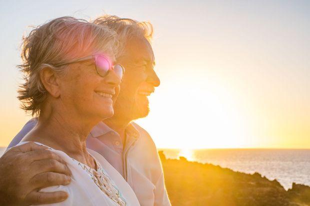 A man and a woman are looking at the sunset over the ocean.